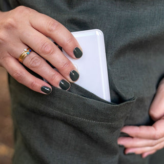 Woman's hand with painted nails and a ring pulling a phone out of a pocket