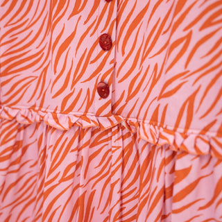 Close up of pink and red patterned dress with buttons and frill