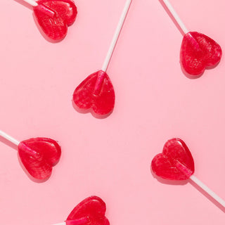 Red heart shaped lollies on a pink background