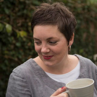 Jules  in a grey top with short hair with a coffee