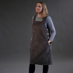 Female wearing Perdita Pinafore Dress Sewing Pattern in Grey Chunky Cord Fabric with Long Sleeve T-Shirt Sewing Pattern Underneath