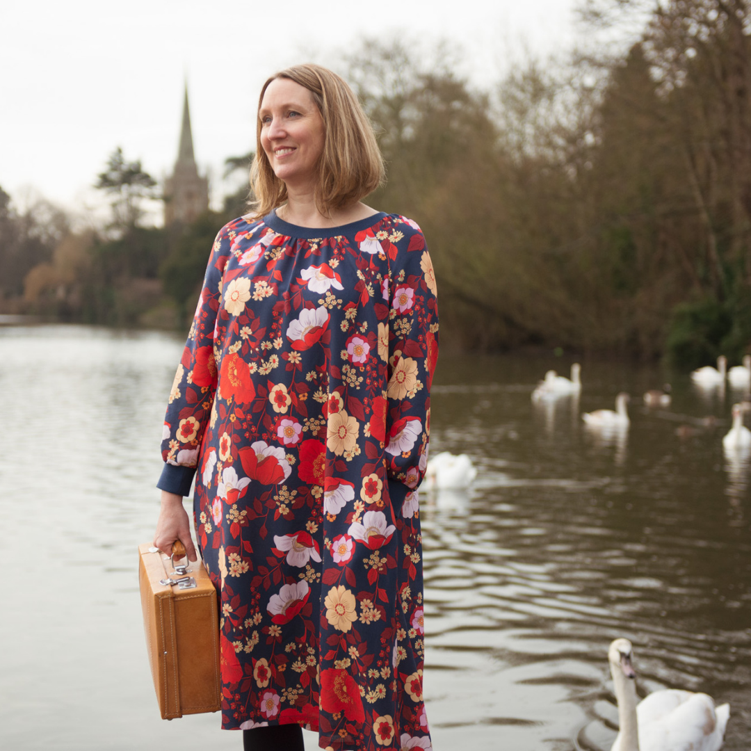 Female wearing the Imogen Dress sewing pattern holding a suitcase