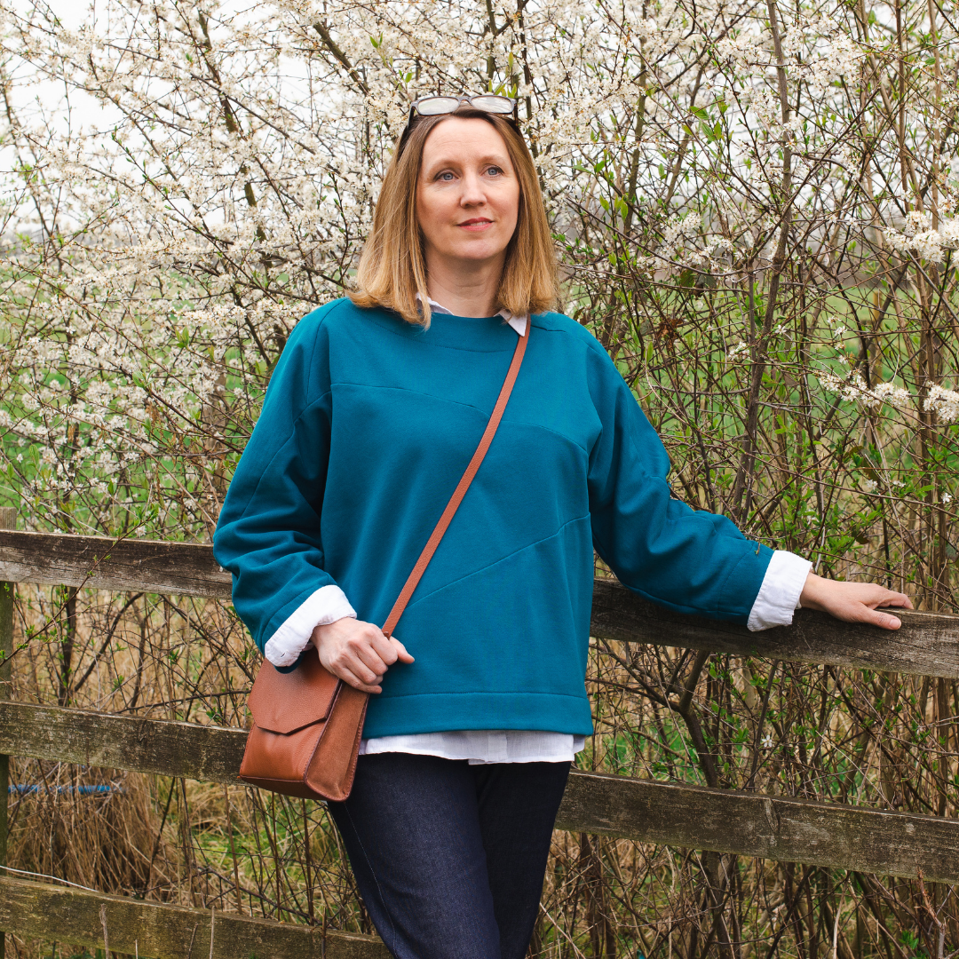 Female leaning on fence wearing the origami sweatshirt sewing pattern